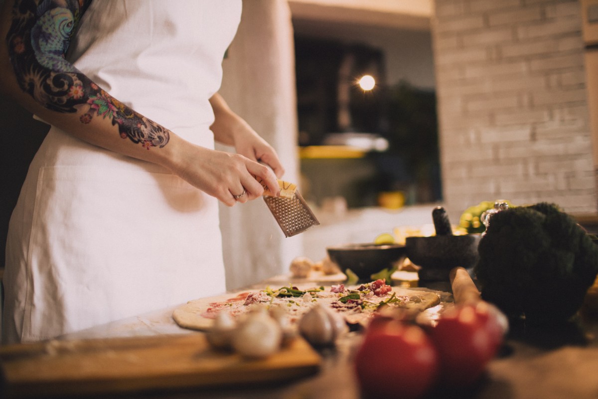 Frau streut Käse über Pizza