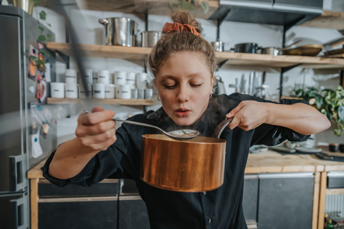 Frau probiert Suppe aus Topf