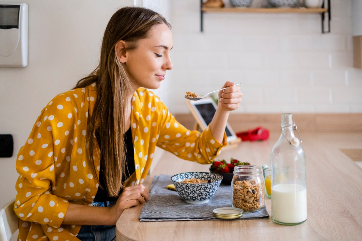 Frau isst Müsli mit Hafermilch