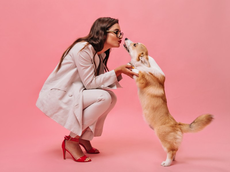 Frau im Anzug küsst einen Hund.