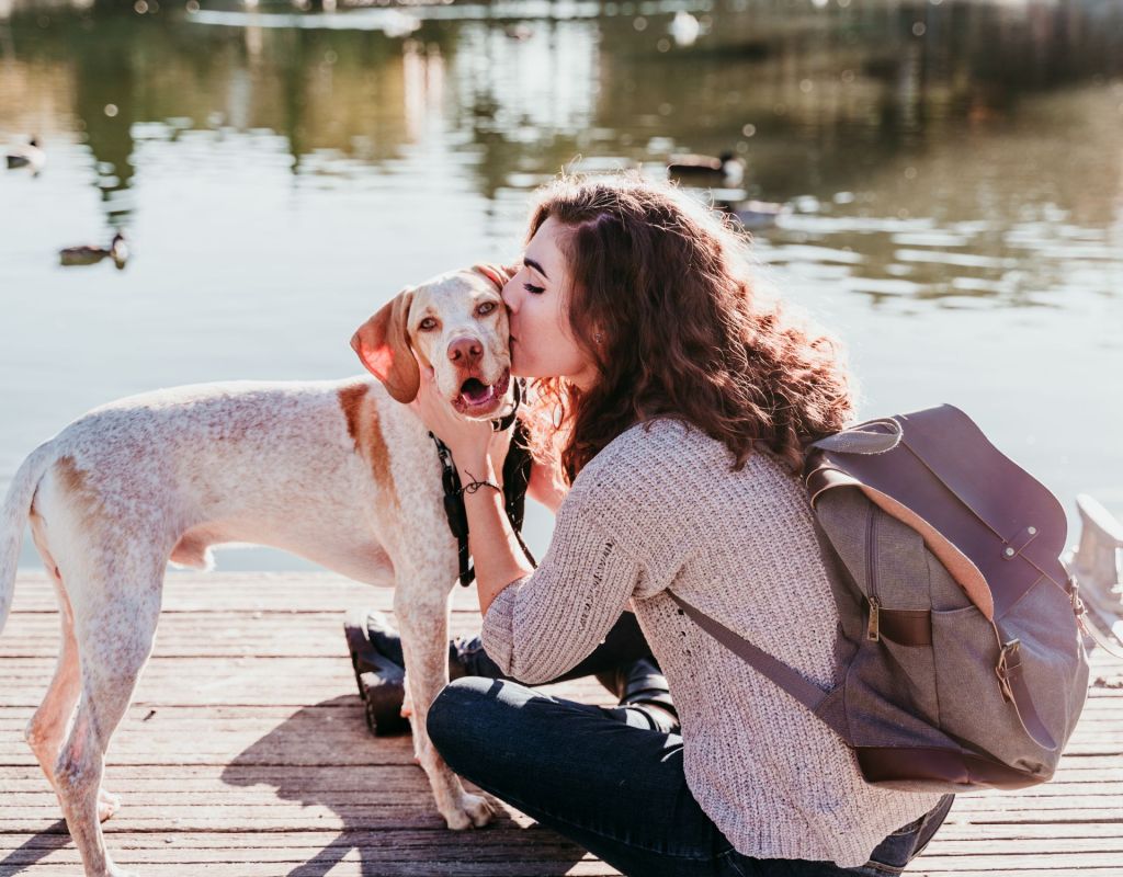 Frau küsst Hund am See