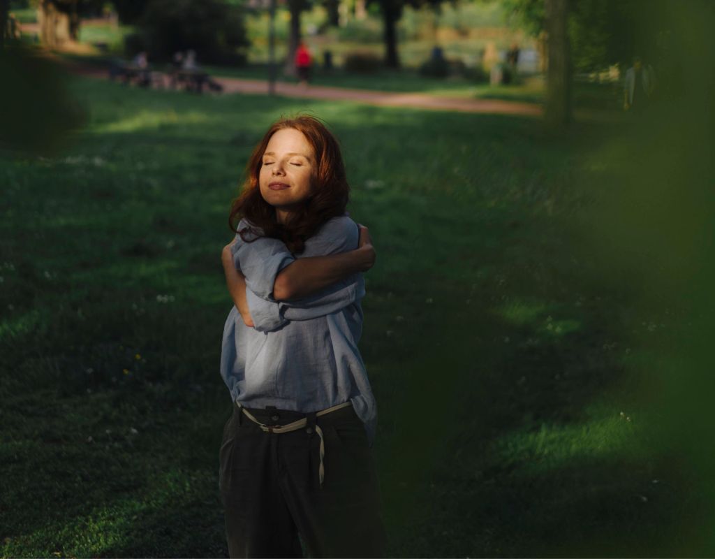 Frau umarmt sich selbst im park