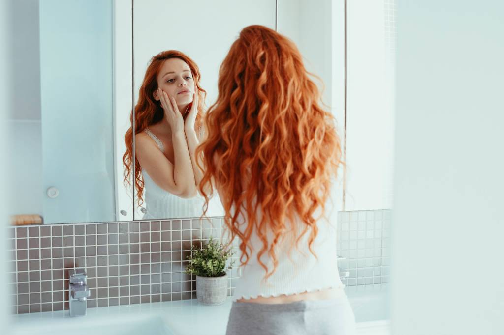 Frau schaut sich ihre Haut im Spiegel an