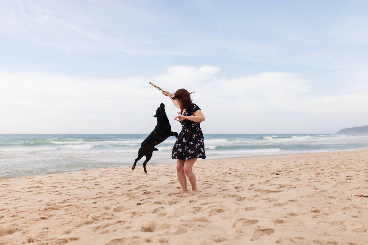 Frau spielt mit Hund am Strand
