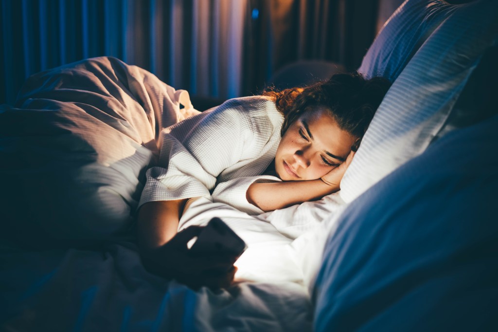 Frau mit Handy im Bett