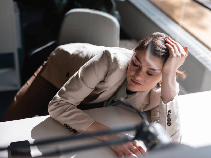 Frau sitzt traurig am Büro-Tisch