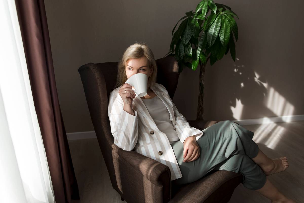Frau sitzt in einem Stuhl und trinkt Kaffee
