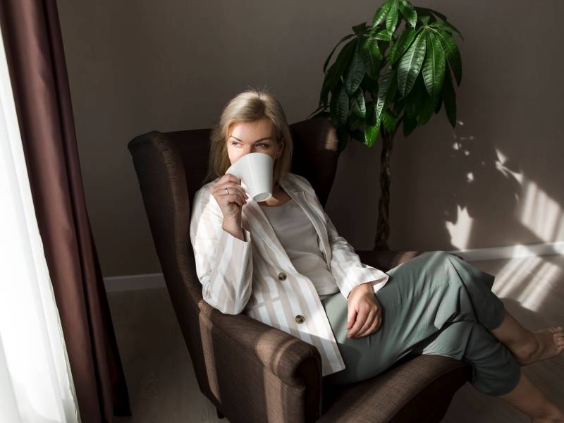 Frau sitzt in einem Stuhl und trinkt Kaffee