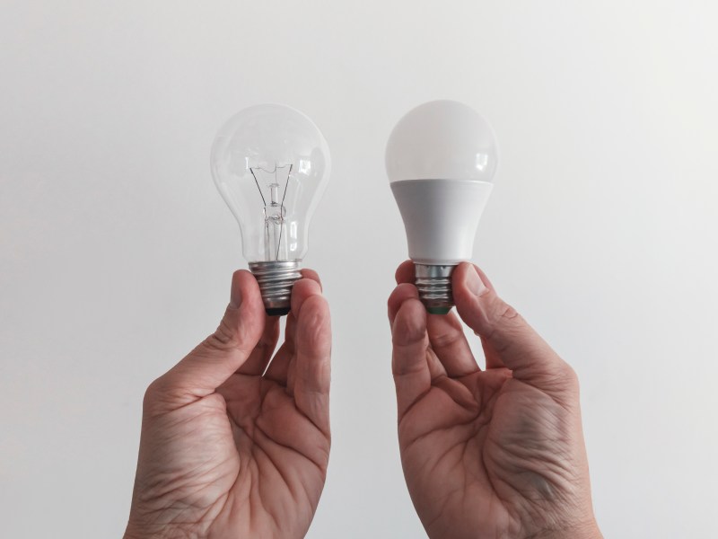 Person hält zwei Energiesparlampen in der Hand.