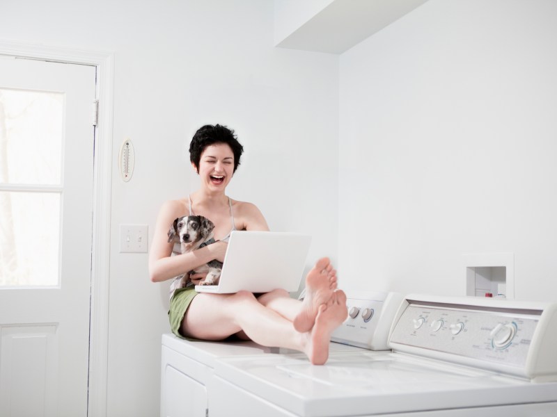 Frau sitzt auf einer Waschmaschine