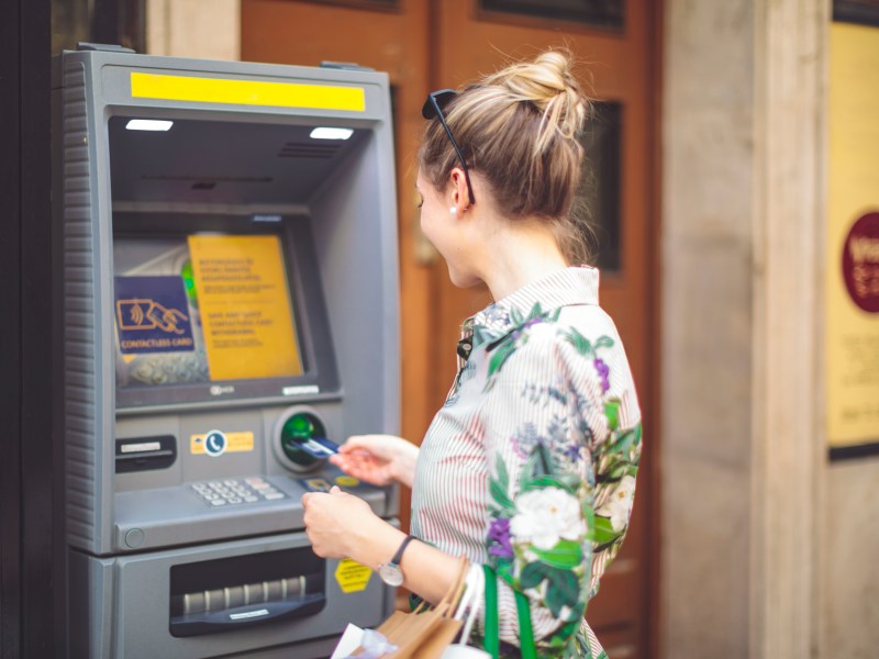 Frau hebt Geld am Automaten ab.