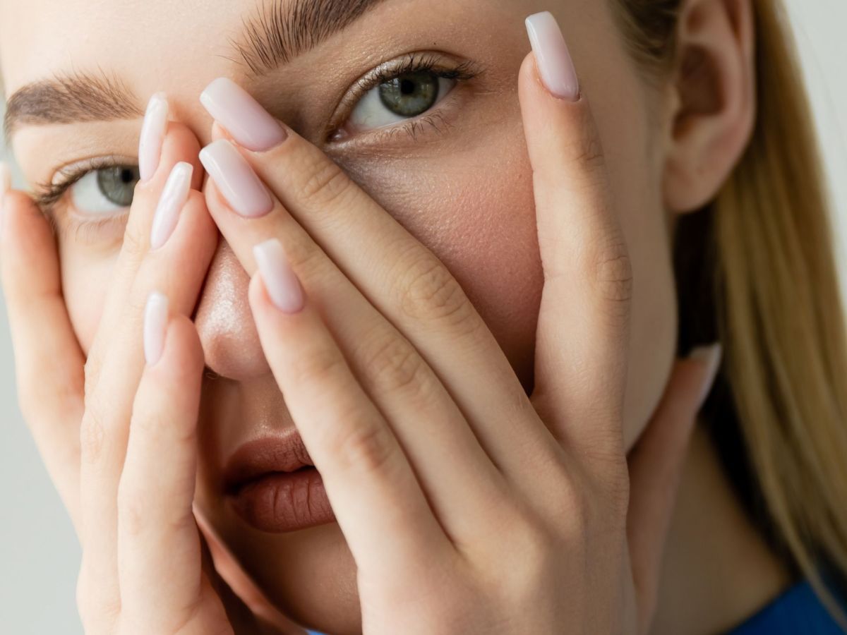 Frau mit Fingern über dem Gesicht: Persönlichkeitstest kleiner Finger