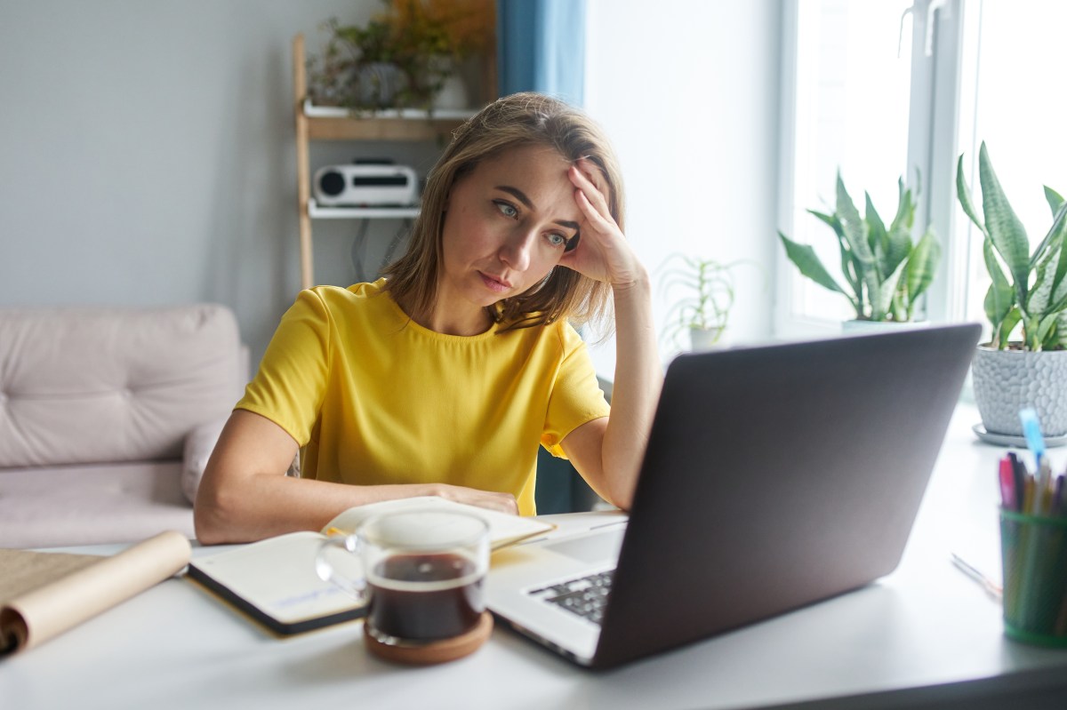 Junge Frau schaut deprimiert auf den Laptop