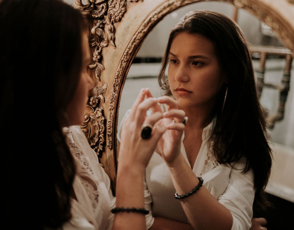 Frau betrachtet sich im Spiegel