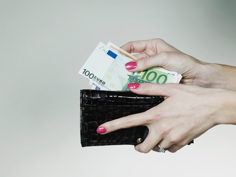 Frau steckt Geldscheine in Portemonnaie