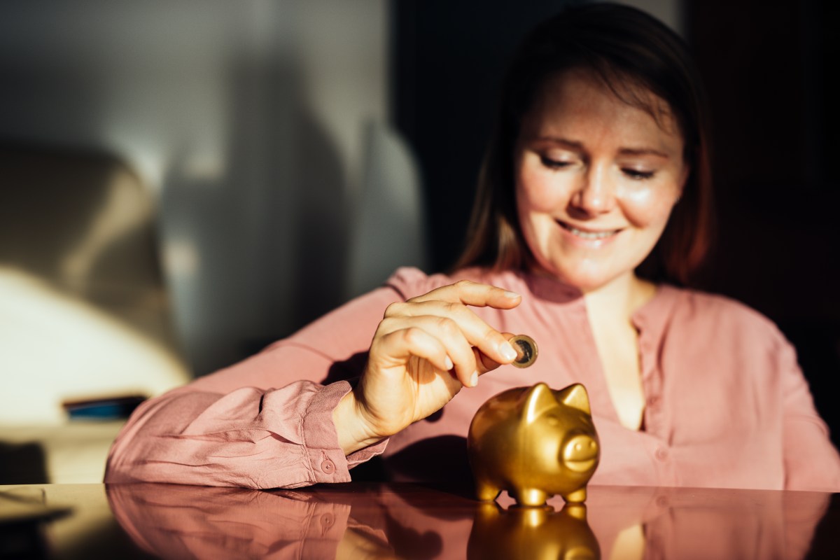 Frau schmeißt Geld in Sparschwein