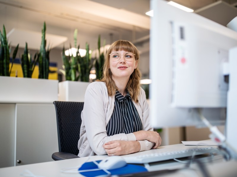 Frau sitzt im Büro an ihrem Arbeitsplatz