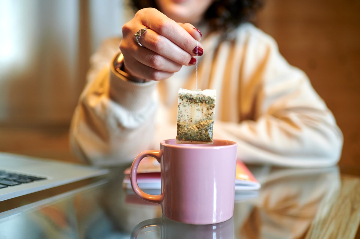 Frau hebt Teebeutel aus der Tasse