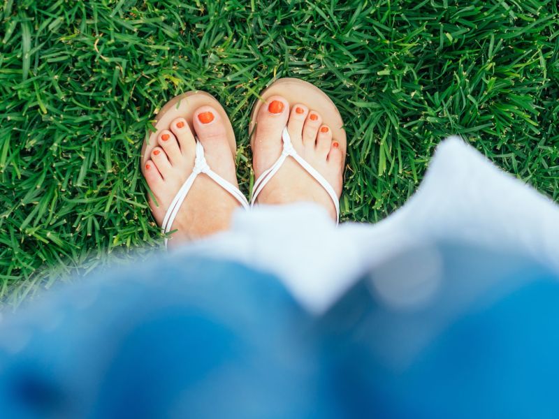 Frau mit Flip Flops und roten Fußnägeln.