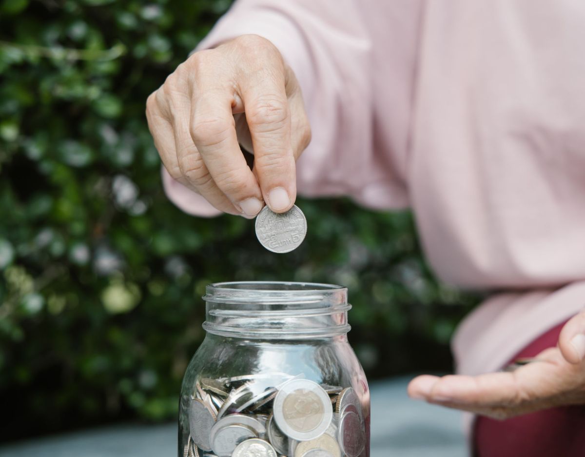 Alte Frau legt Geld in ein Glas