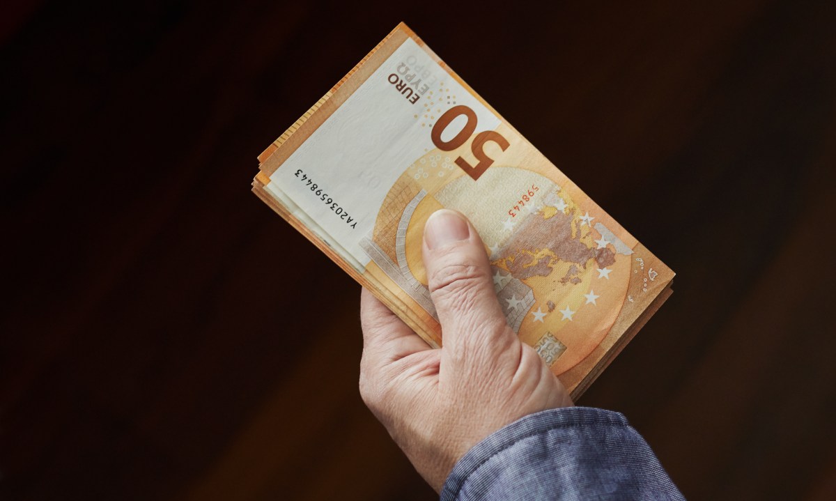 Eine Person hält mehrere 50-Euro-Scheine in der Hand.