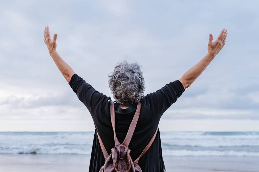 Rentnerin streckt am Meer ihre Arme aus