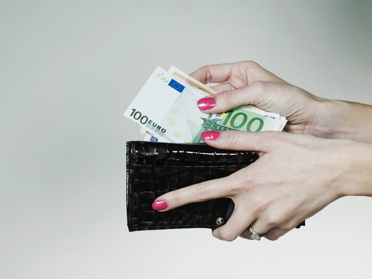 Frauenhand nimmt Geld aus dem Portemonnaie