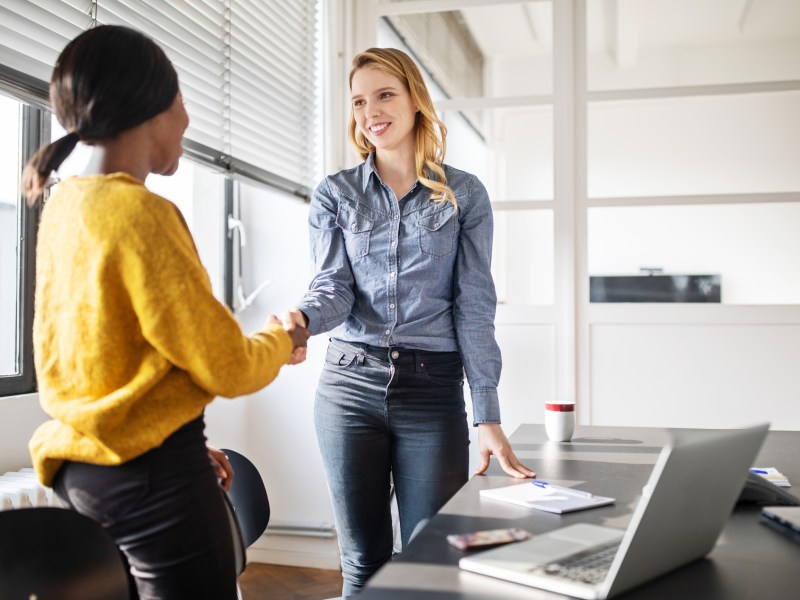 Frau schüttelt eine Frau im Büro die Hand.