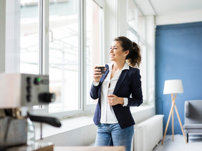 Frau trinkt im Büro eine Tasse Kaffee.