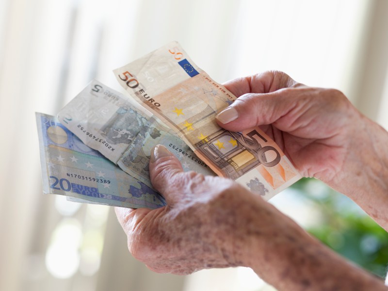 Ältere Hand hält mehrere Euro-Scheine.