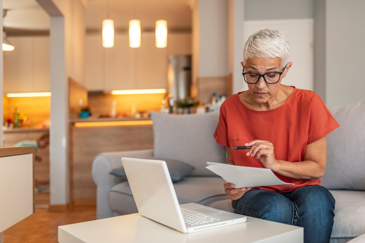 Eine ältere Frau sitzt vor dem laptop und füllt einen Antrag aus.