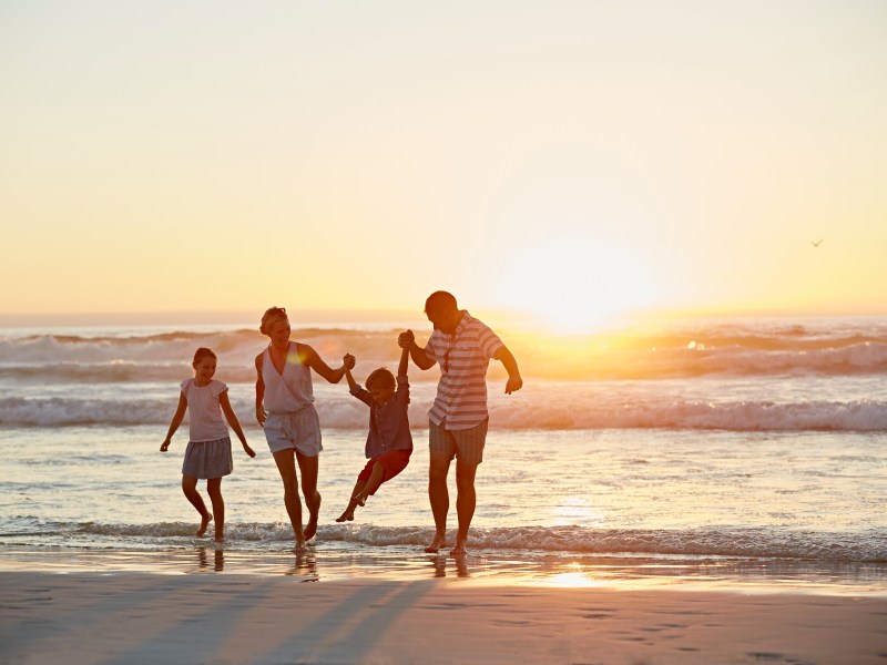 Familie bei Sonnenuntergang am Strand.