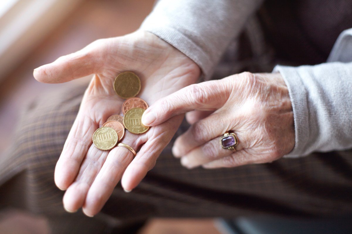 In der Hand einer Seniorin liegen mehrere Münzen.