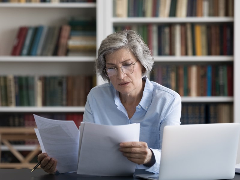 Ältere Frau im Büro hält Dokument in der Hand.