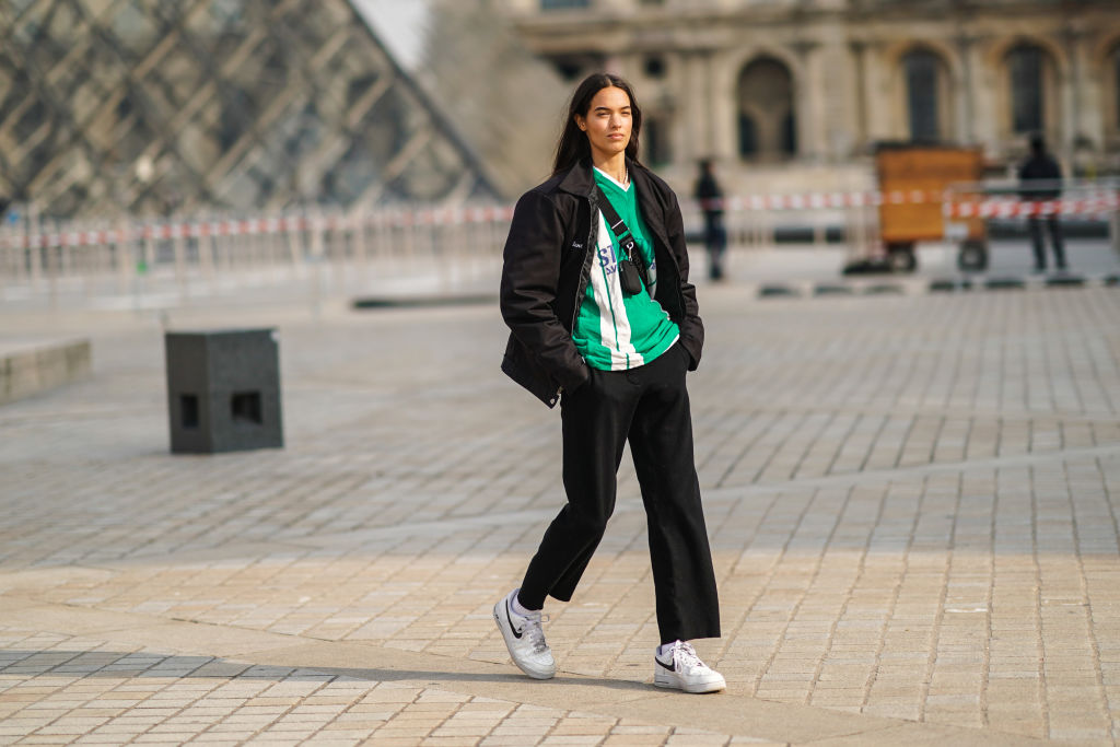 Modetrend2025: Frau mit schwarzer Hose, weißen Schuhe und grünen Shirt.