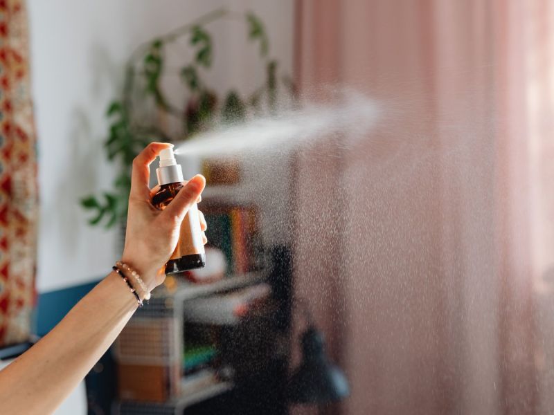 Frau sprüht ein Spray in einen Raum.