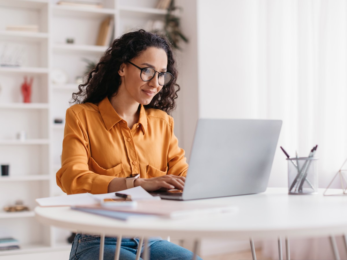 Frau mit Brille sitzt am Laptop.