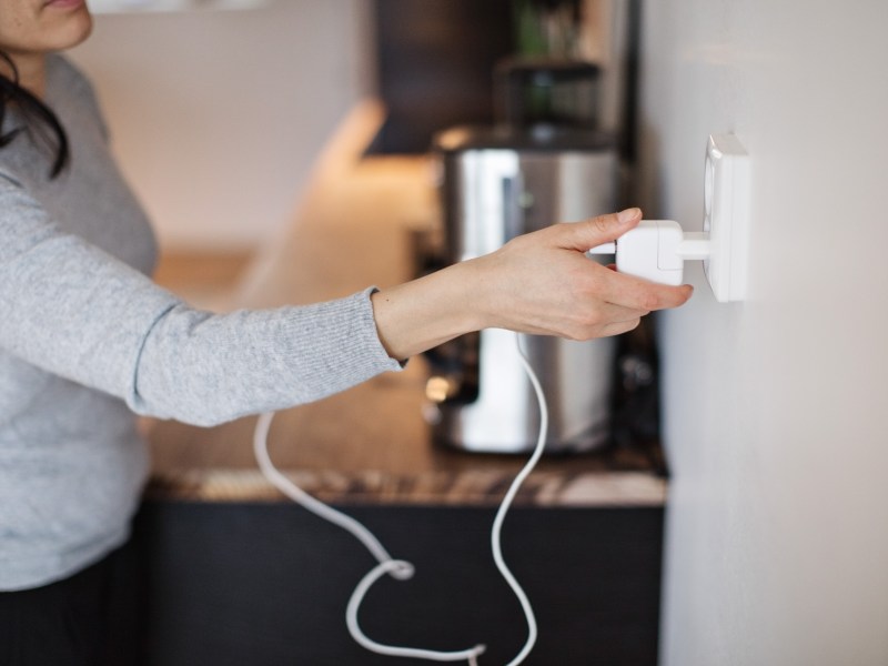 Eine Frau steckt einen Stecker aus der Steckdose.