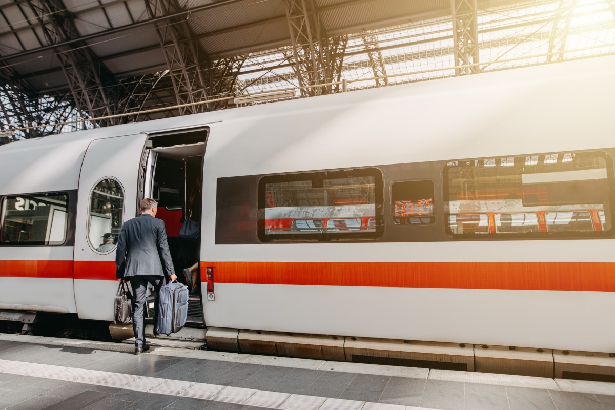 Ein Mann steigt mit zwei Koffern in einen ICE der Deutschen Bahn.