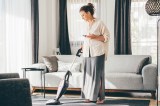 Eine Frau saugt das Wohnzimmer.