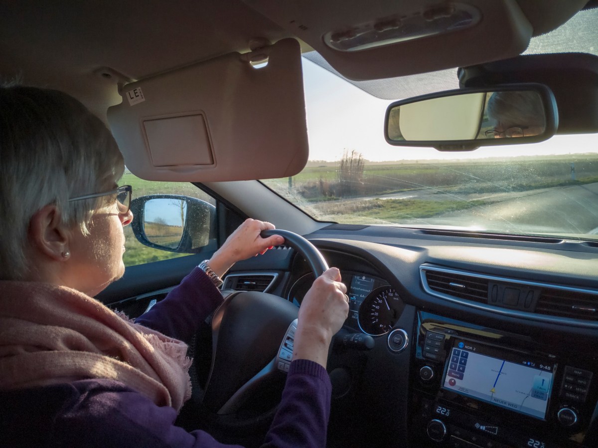 Eine Seniorin sitzt am Steuer eines Autos.