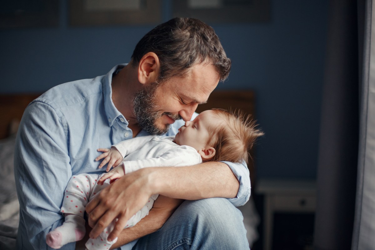 Vater küsst Baby auf den Kopf.