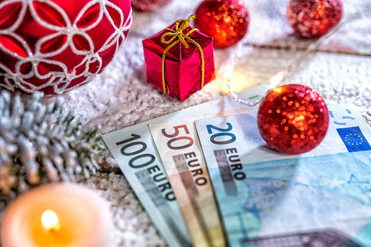Geldscheine liegen auf einem weihnachtlich geschmückten Tisch.