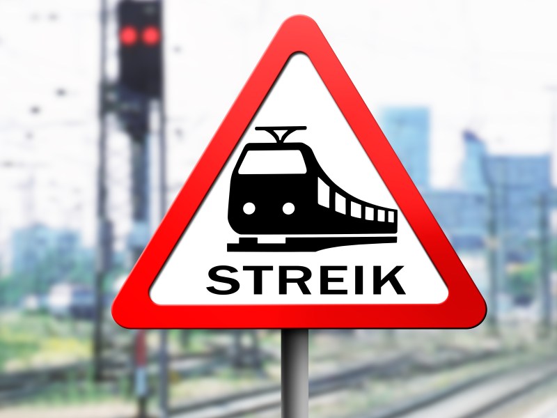 Auf einem Warnschild ist ein Zug abgebildet mit der Aufschrift "Streik".