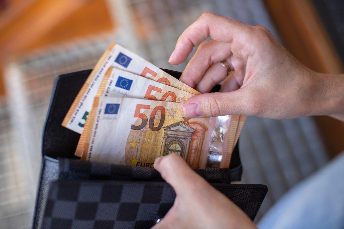 Eine Person zieht drei 50-Euro-Scheine aus einem Portemonnaie.