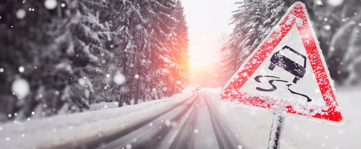 Eine Straße voller Schnee. Daneben steht ein Warnschild.