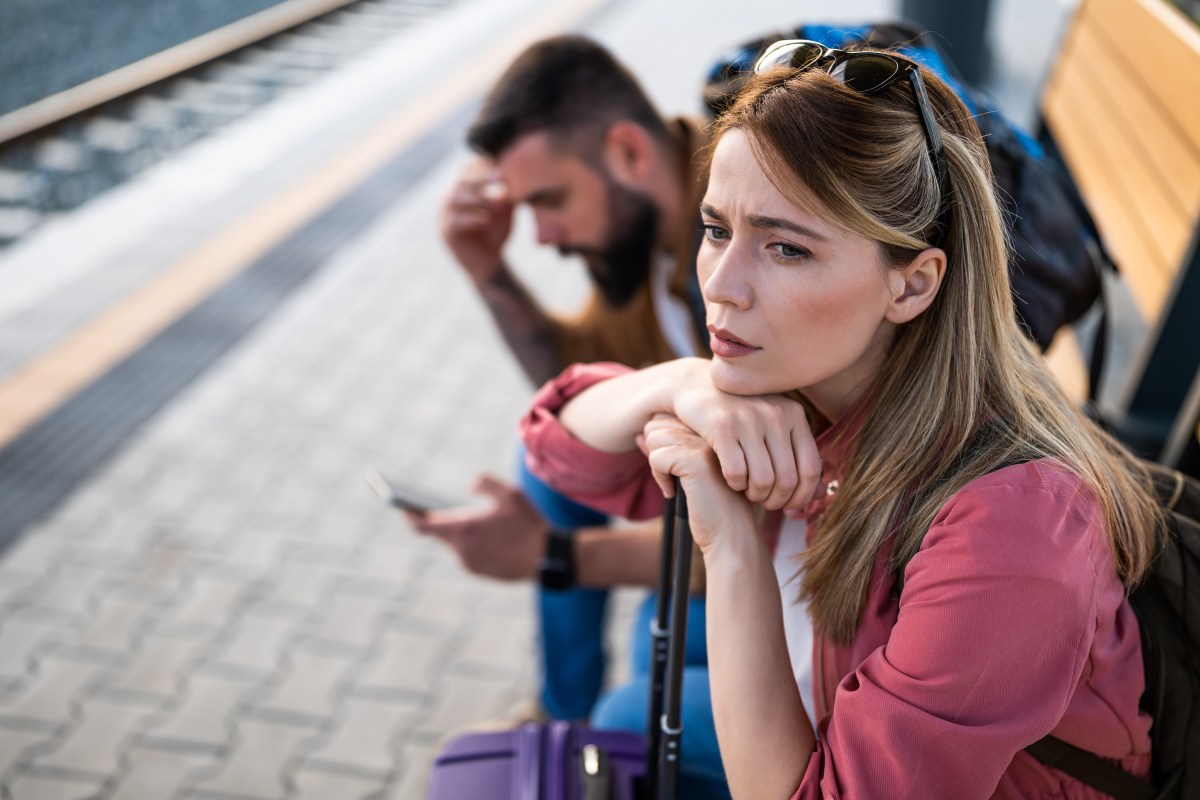 Zwei Reisende sitzen deprimiert am Bahnsteig.