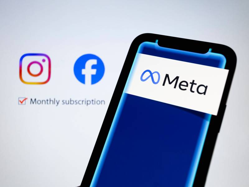 Auf einem Smartphone erscheint das Logo des Unternehmens Meta. Im Hintergrund sind die Logos von Instagram und Facebook zu sehen.