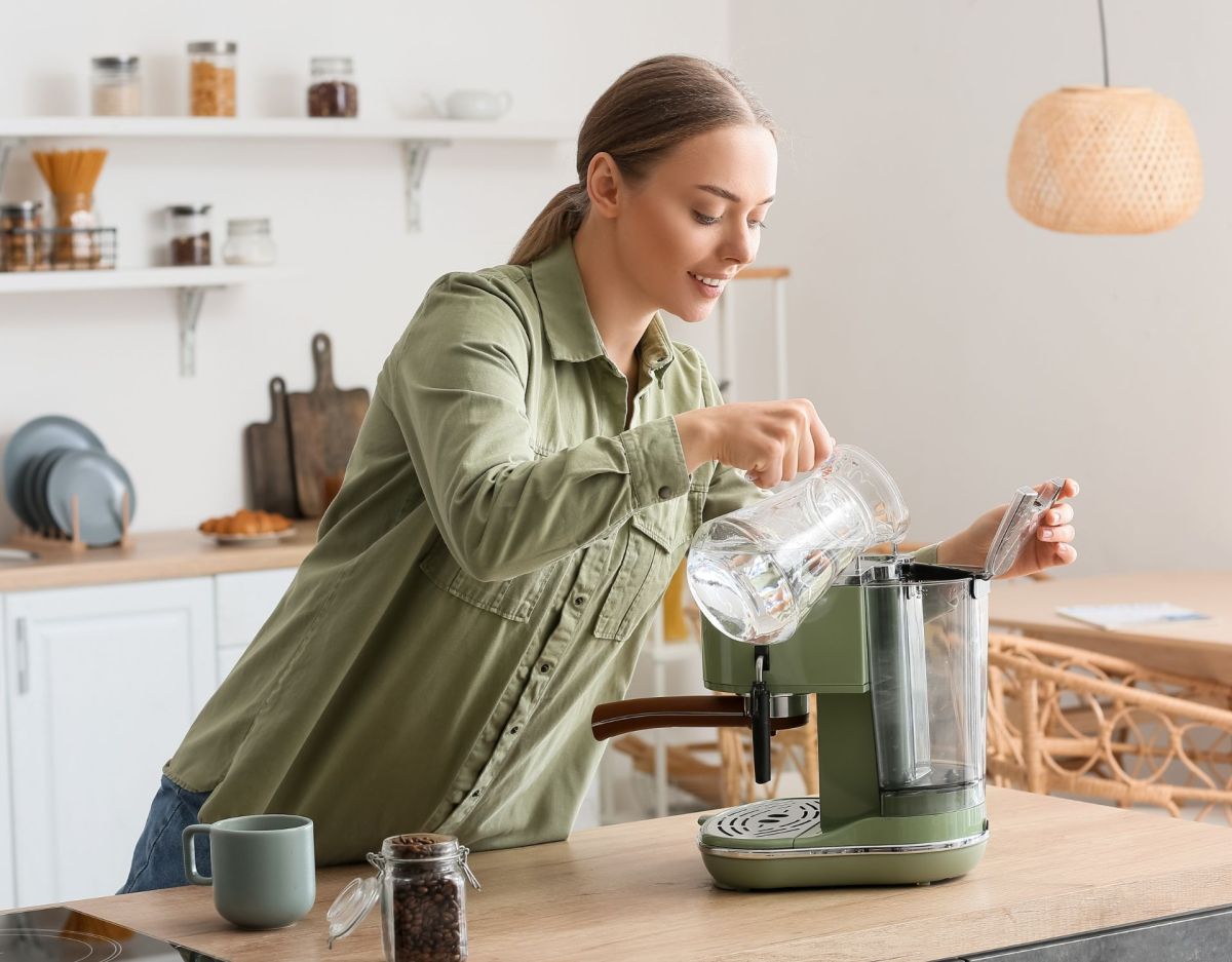 Frau füllt Wasser in eine Kaffeemaschine