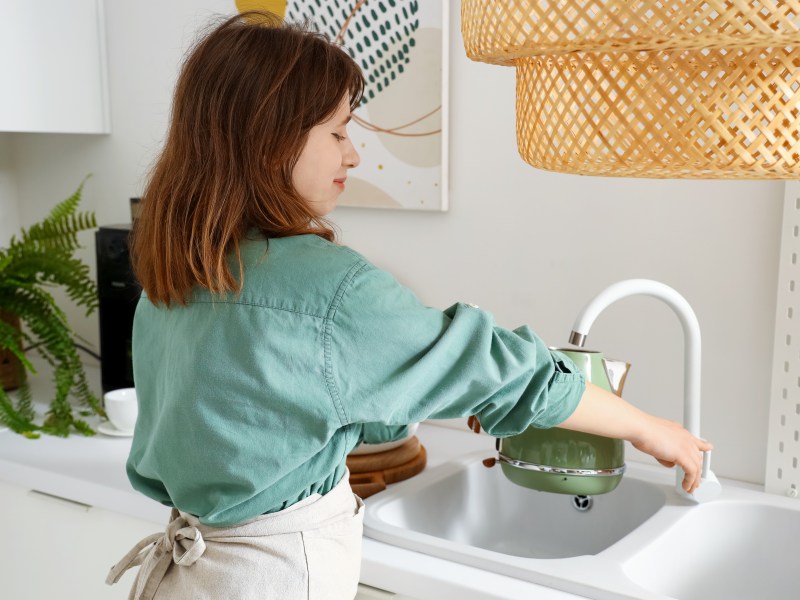Frau befüllt Wasserkocher